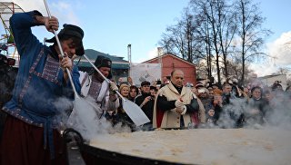 Участники масленичных гуляний во время установления рекорда по приготовлению самого большого блина России в саду Эрмитаж в Москве